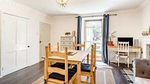 A dining area with a wooden table and chairs, a chandelier, a desk with a computer, and a view through a window. - 2 bedroom accommodation in Berwick Upon Tweed (Berwick Upon Tweed)