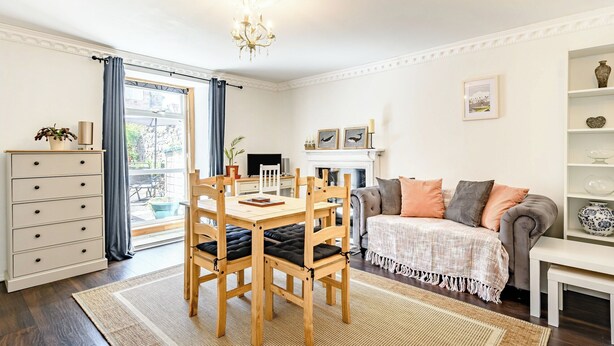 A cozy living room with a dining area, a fireplace, and a large window with curtains. - 2 bedroom accommodation in Berwick Upon Tweed (Berwick Upon Tweed)