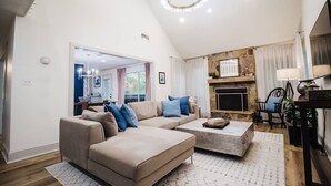 A spacious living room with a large sectional sofa, a fireplace, and a dining area with a table and chairs. - Stunning Lake House 4Bdm w/ Sandy Beach Access (Pottsboro)