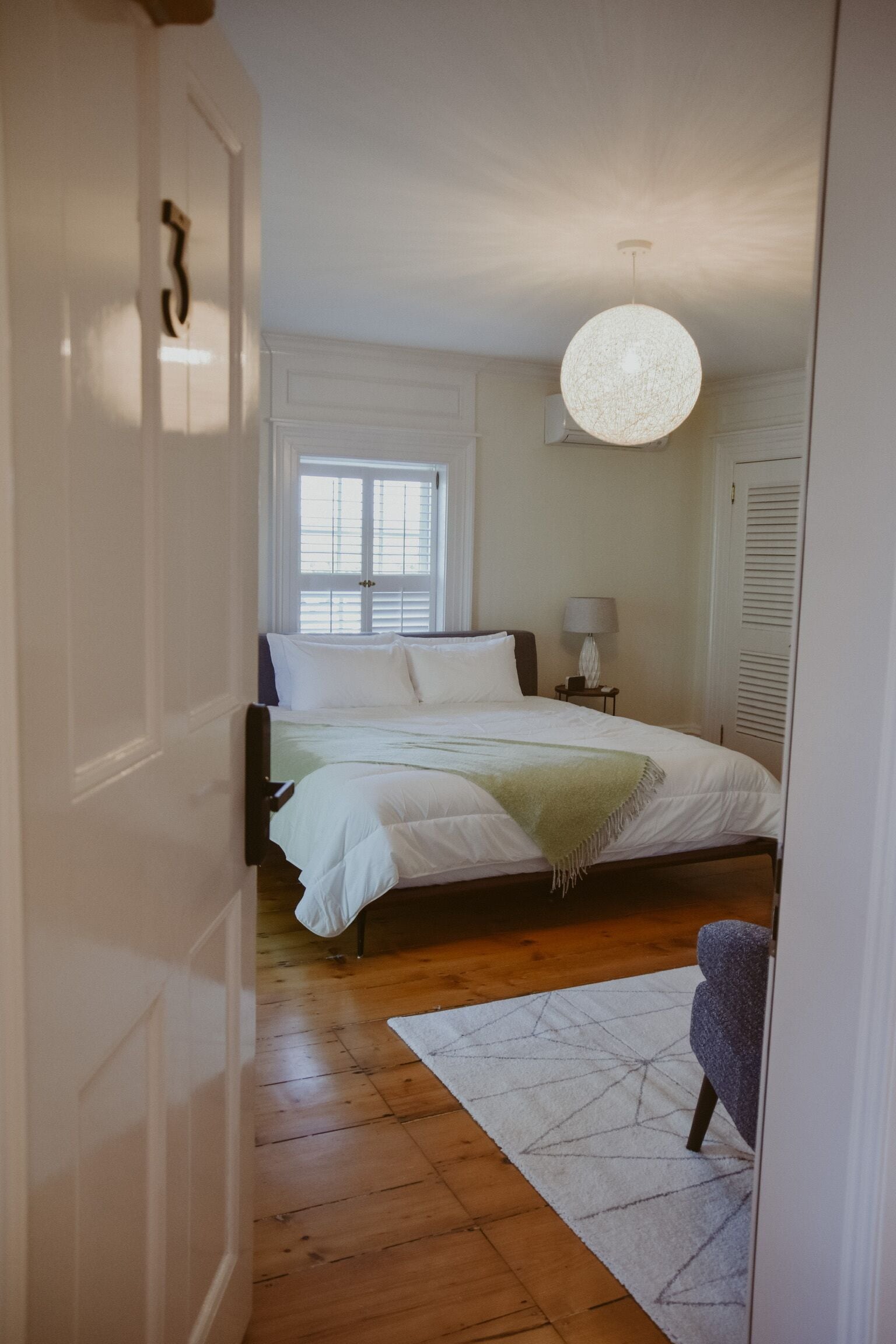 Une chambre à coucher avec un lit, une table de chevet, une lampe et une chaise.