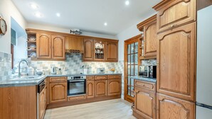 A kitchen with wooden cabinets, a built-in oven, and a tiled backsplash. - Lovely detached property in a rural location on the Welsh border. (Llanfihangel Nant Melan, near Presteigne)