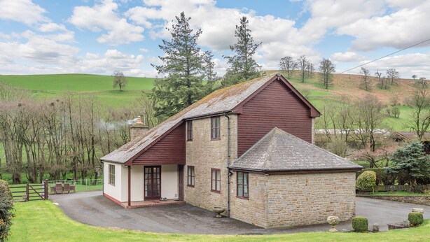 A stone building with a red roof, a small porch, and a paved driveway. - Lovely detached property in a rural location on the Welsh border. (Llanfihangel Nant Melan, near Presteigne)