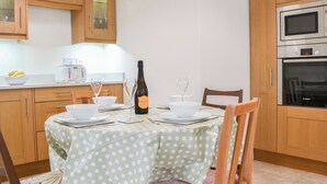 A kitchen with wooden cabinets, a dining table with a polka dot tablecloth, and a Bosch oven.