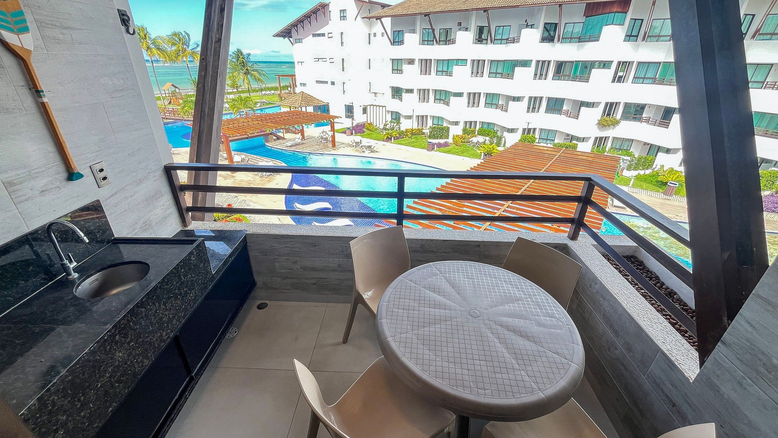 A balcony with a view of a swimming pool and a building with multiple balconies.