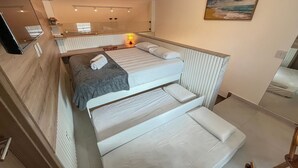 A bunk bed room with a small desk, a mirror, and a painting of a beach scene. - Maui Beach Residence (Tamandaré)