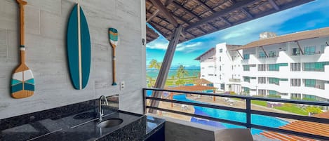 A modern bathroom with a large window overlooking a pool and a building.