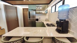 A kitchen with a countertop, a water dispenser, a stove, and a refrigerator. - Maui Beach Residence (Tamandaré)