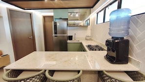 A kitchen with a countertop, a water dispenser, a stove, and a refrigerator. - Maui Beach Residence (Tamandaré)