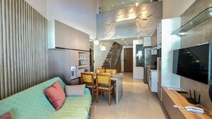 A modern interior with a sofa, dining table, chairs, kitchen area, and a TV. - Maui Beach Residence (Tamandaré)