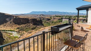 A balcony with a view of a canyon and mountains. There are outdoor seating areas with tables and chairs. - Incredible View #5 at The Dwellings (La Verkin)