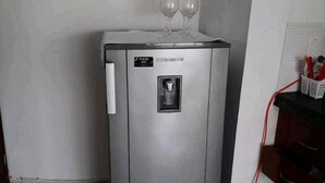 Ein kleiner Kühlschrank mit Wasserspender und einem Weinglashalter auf der Oberseite.