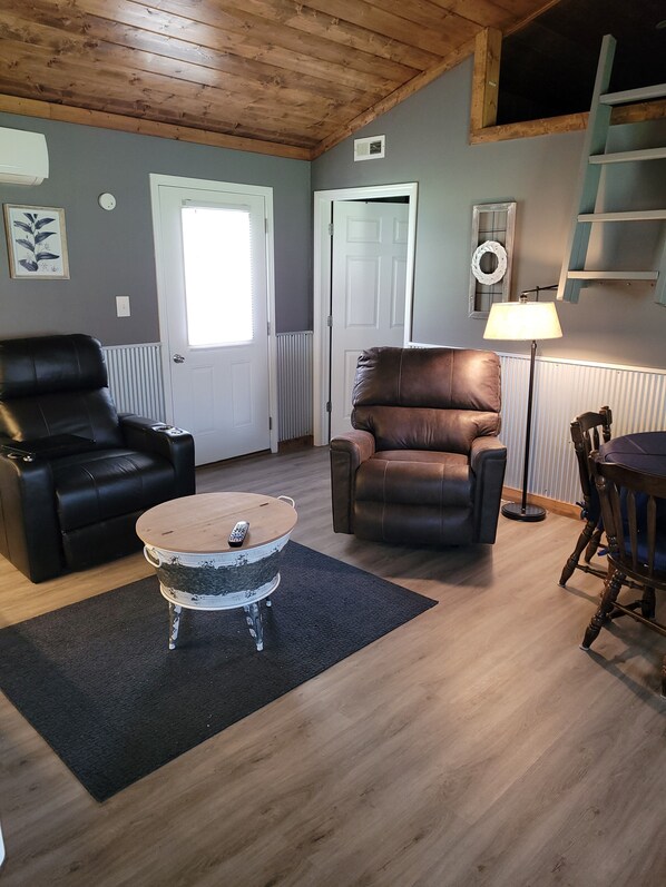 Un salon comprenant deux canapés en cuir, une table basse, une lampe et une table à manger avec des chaises.