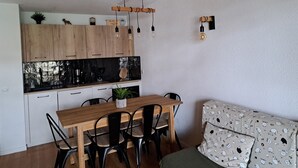 Cozinha moderna com armários de madeira, bancada preta e lâmpadas penduradas.