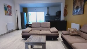 Una sala de estar con un sofá modular, una mesa de centro y una cocina al fondo.