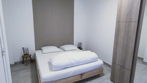 Un dormitorio minimalista con cama, dos mesitas de noche y un armario.
