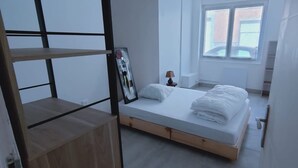 Un dormitorio con cama, una estantería de madera, una ventana y una puerta.