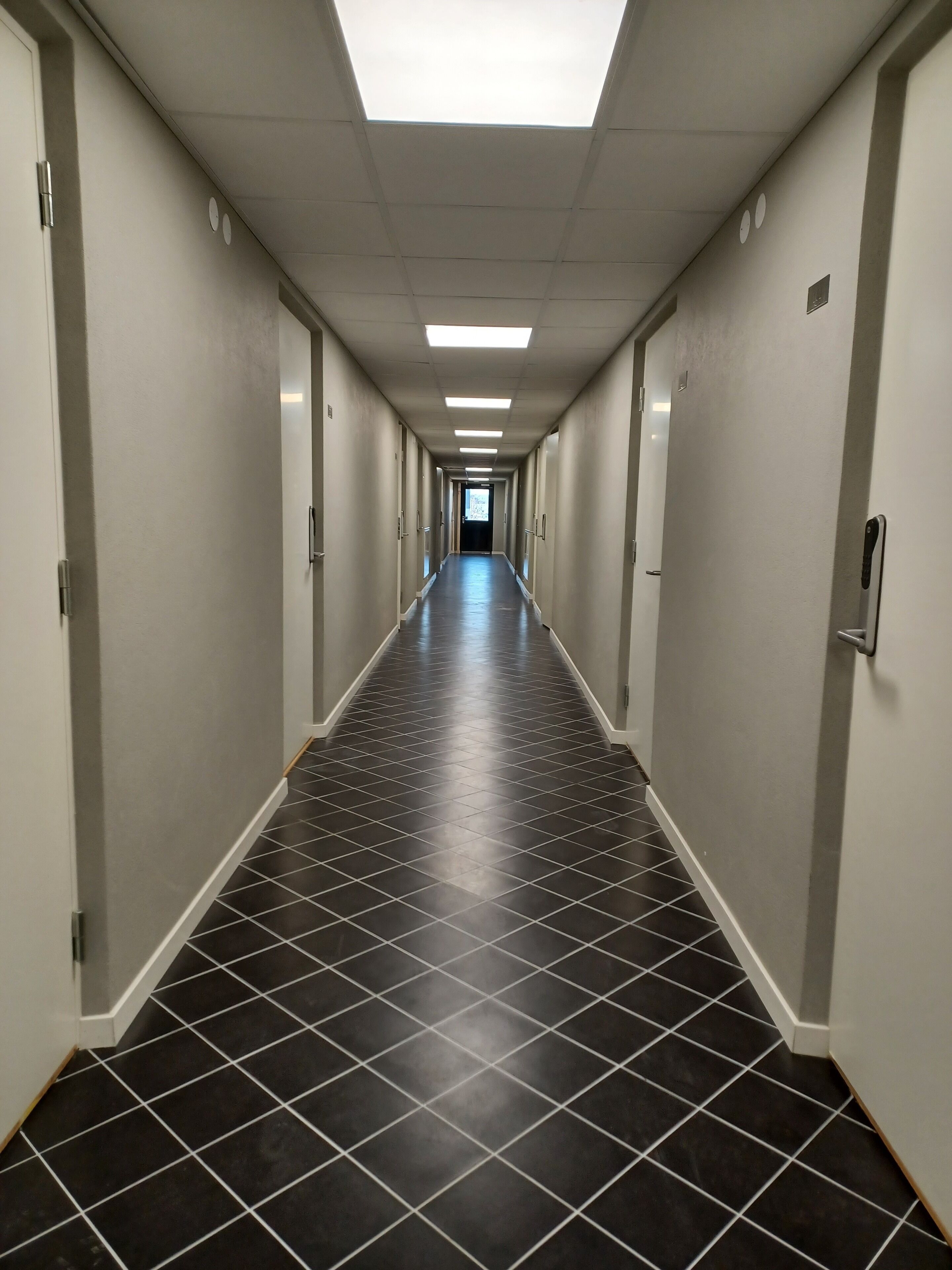 En lång, smal hall med ett klinkergolv och ett takfönster i änden.