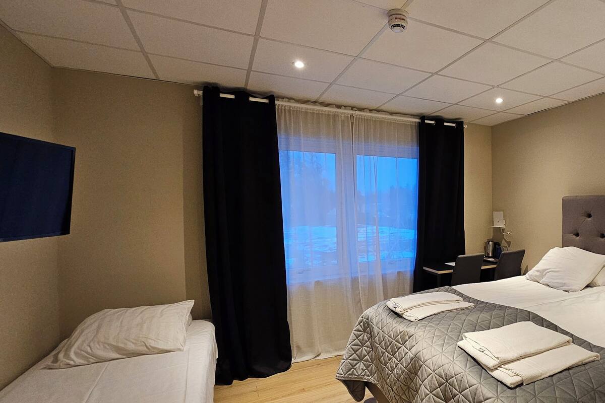 A hotel room with a large bed, a desk, and a TV mounted on the wall.