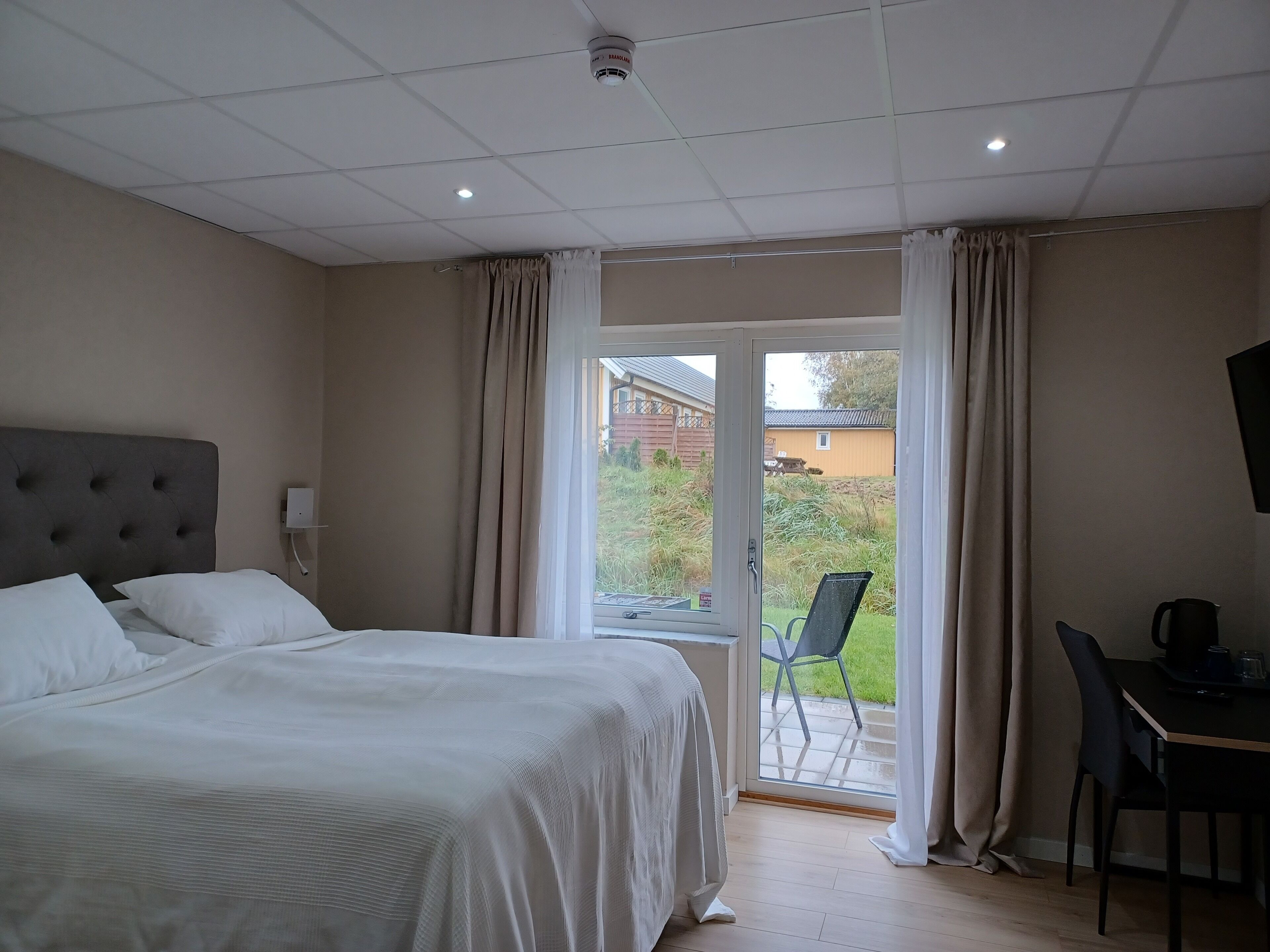 A hotel room with a bed, a desk, and a view of the outside.