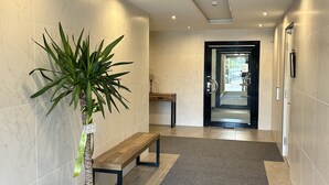A hallway with a bench, a potted plant, and a door leading to another area. - Hotell Solstickan Mellbystrand (Mellbystrand)