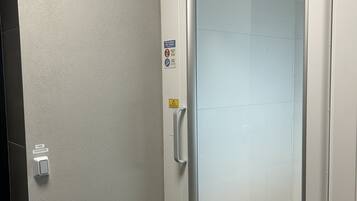 A modern elevator with a glass door, a handrail, and a control panel labeled "HISS ELEVATOR".