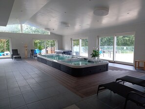 Un amplio espacio interior con jacuzzi, asientos y ventanas grandes que ofrecen vistas al exterior.