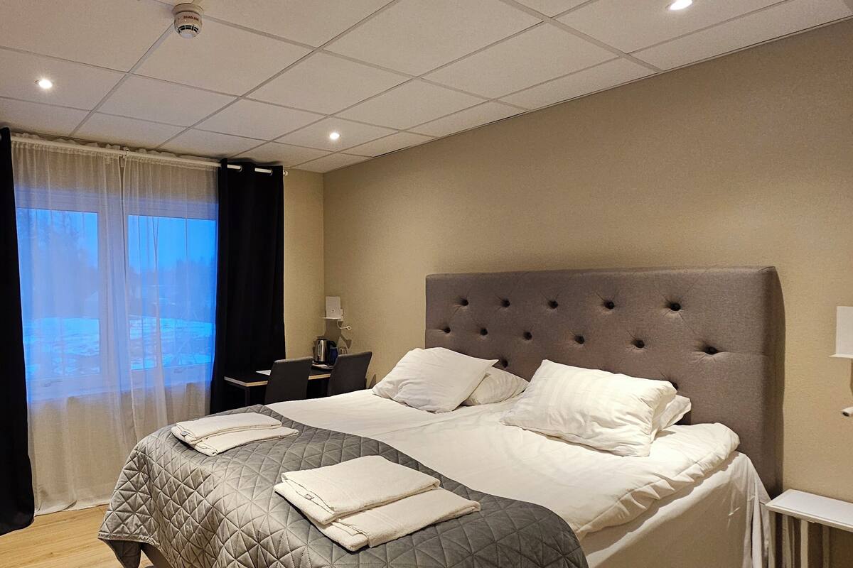 A hotel room with a large bed, a desk, and a chair.