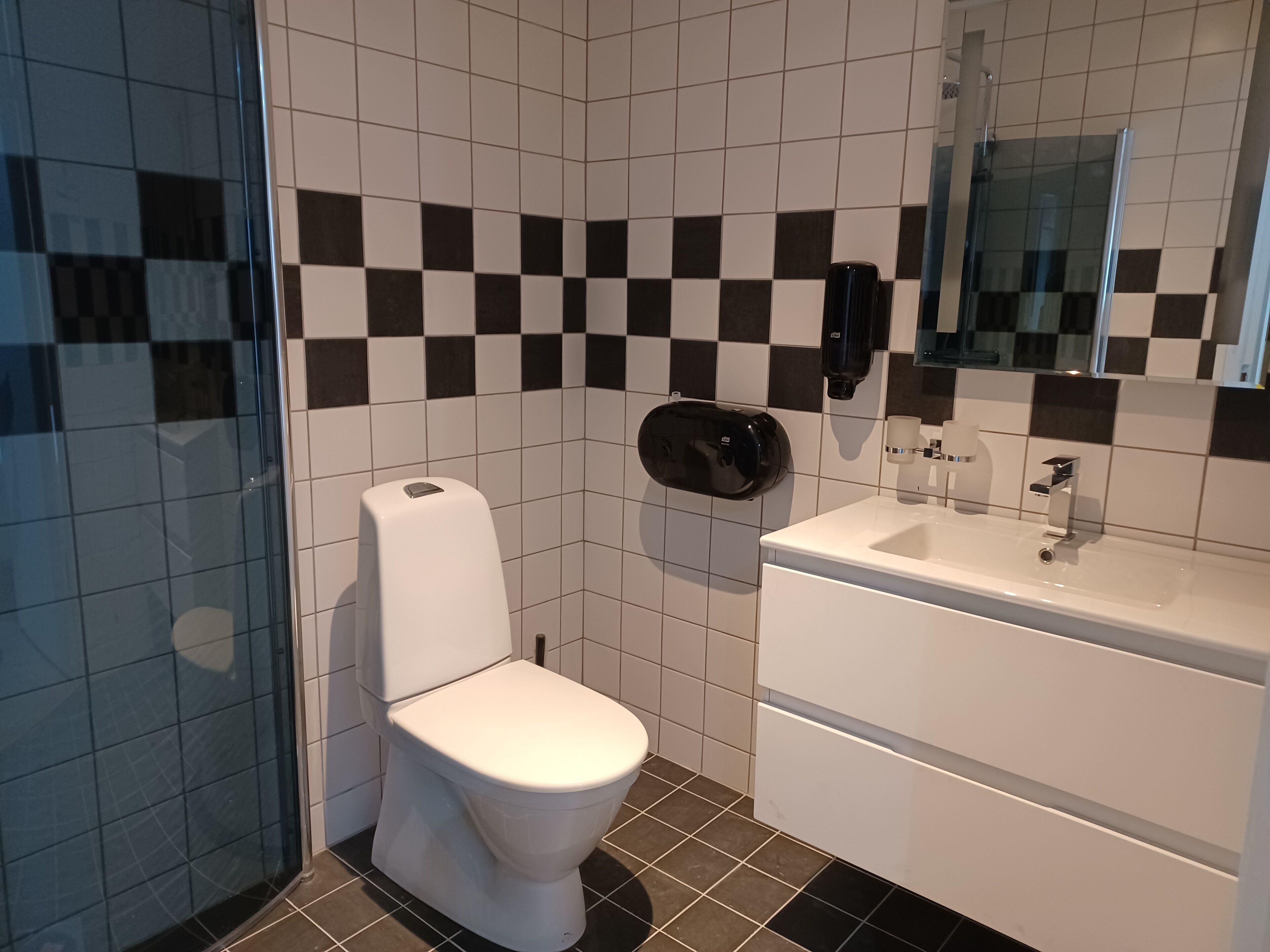 Un baño moderno con inodoro, lavabo y cabina de ducha de vidrio.