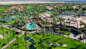 Un parcours de golf avec une piscine, des palmiers et un paysage désertique en arrière-plan.