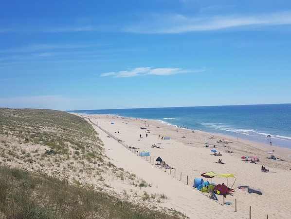 A beach with tents and umbrellas, a sandy shore, and a clear sky.
