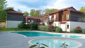 A residential area with a swimming pool, wooden houses, and a fenced garden.