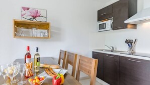 A modern kitchen with dark cabinets, a microwave, and a wooden dining table set with food and drinks.