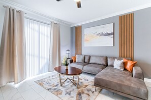 A modern living room with a sectional sofa, a coffee table, and a large abstract painting on the wall.
