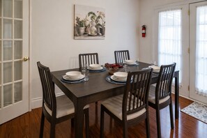 Ein Esszimmer mit einem dunklen Holztisch, gedeckt für sechs Personen, umgeben von sechs Stühlen mit gepolsterten Sitzen.