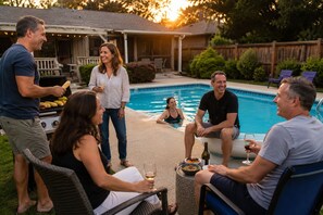 Eine Gruppe von Personen an einem Pool mit Grill, Esstisch und Stühlen.