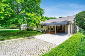 A single-story house with a porch, a paved driveway, and a well-maintained lawn.