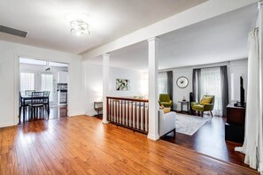 A spacious living area with hardwood floors, a dining table, and a staircase leading to another level.
