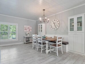 Enjoy meals in this dining area with a wooden table and comfortable chairs, surrounded by stylish cabinetry and a chandelier.