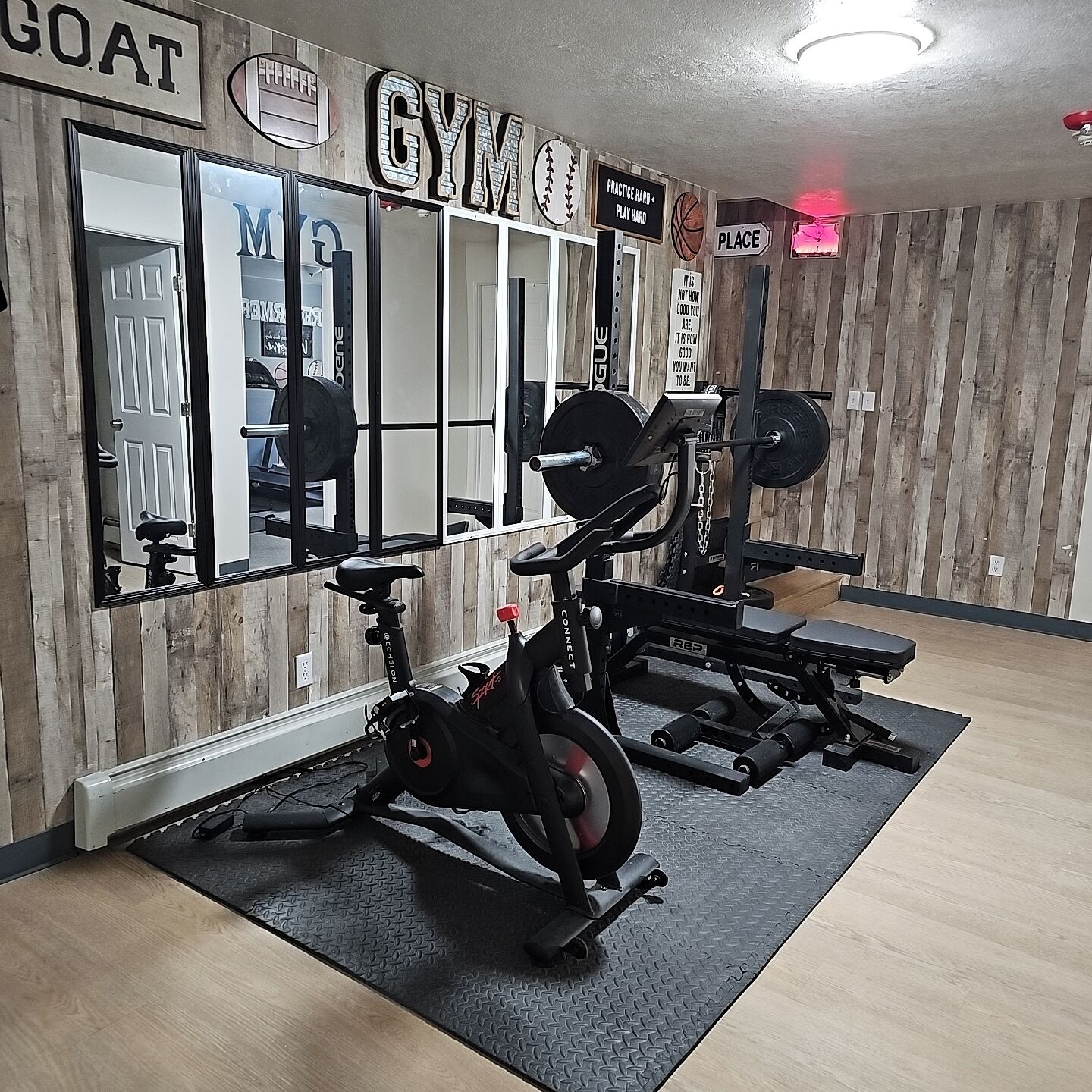 A gym with exercise equipment, a mirrored wall, and motivational signs.