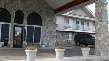 Um edifício de pedra com varanda e um SUV preto estacionado em frente.