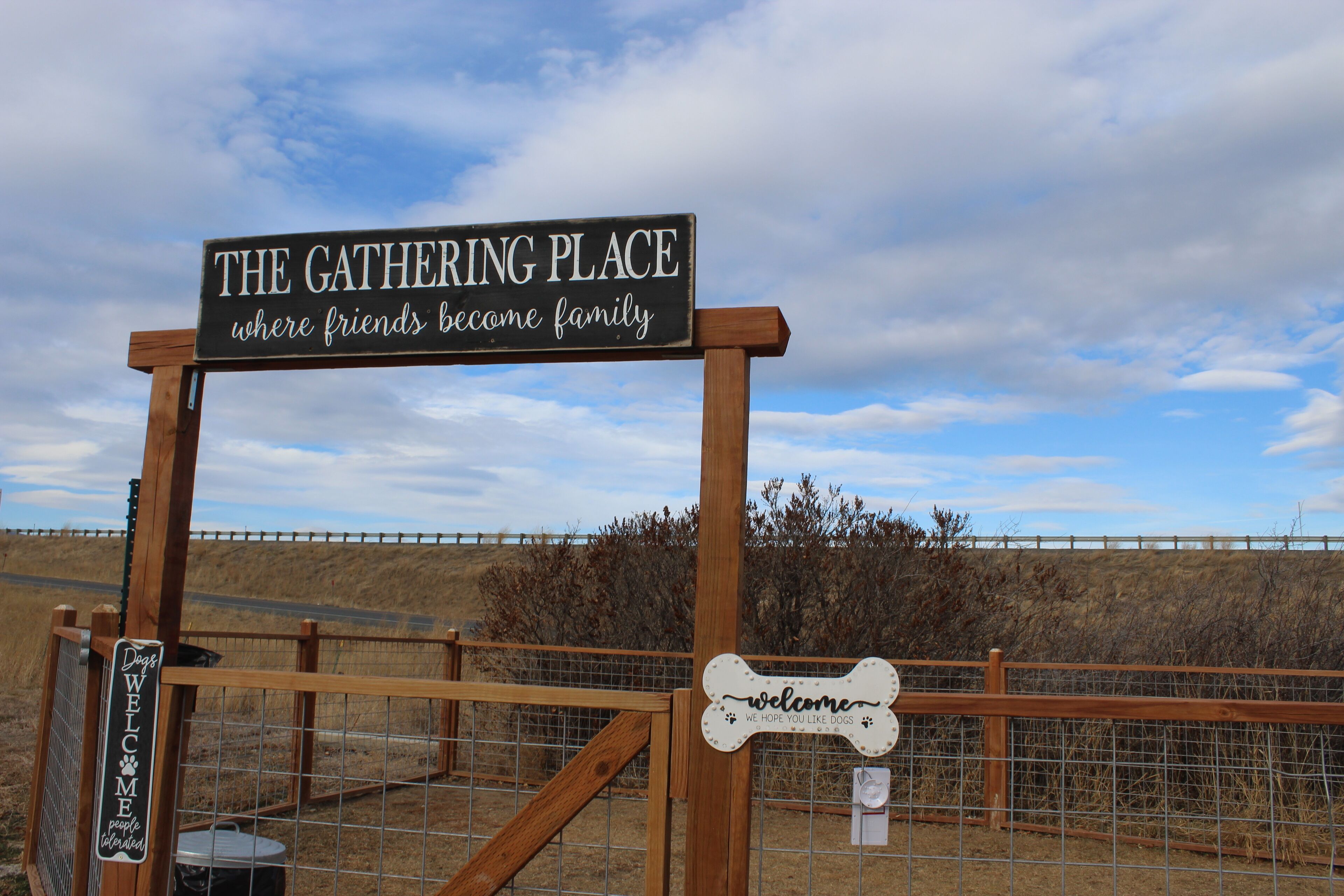 A sign that reads "The Gathering Place where friends become family" with a welcome sign for dogs.