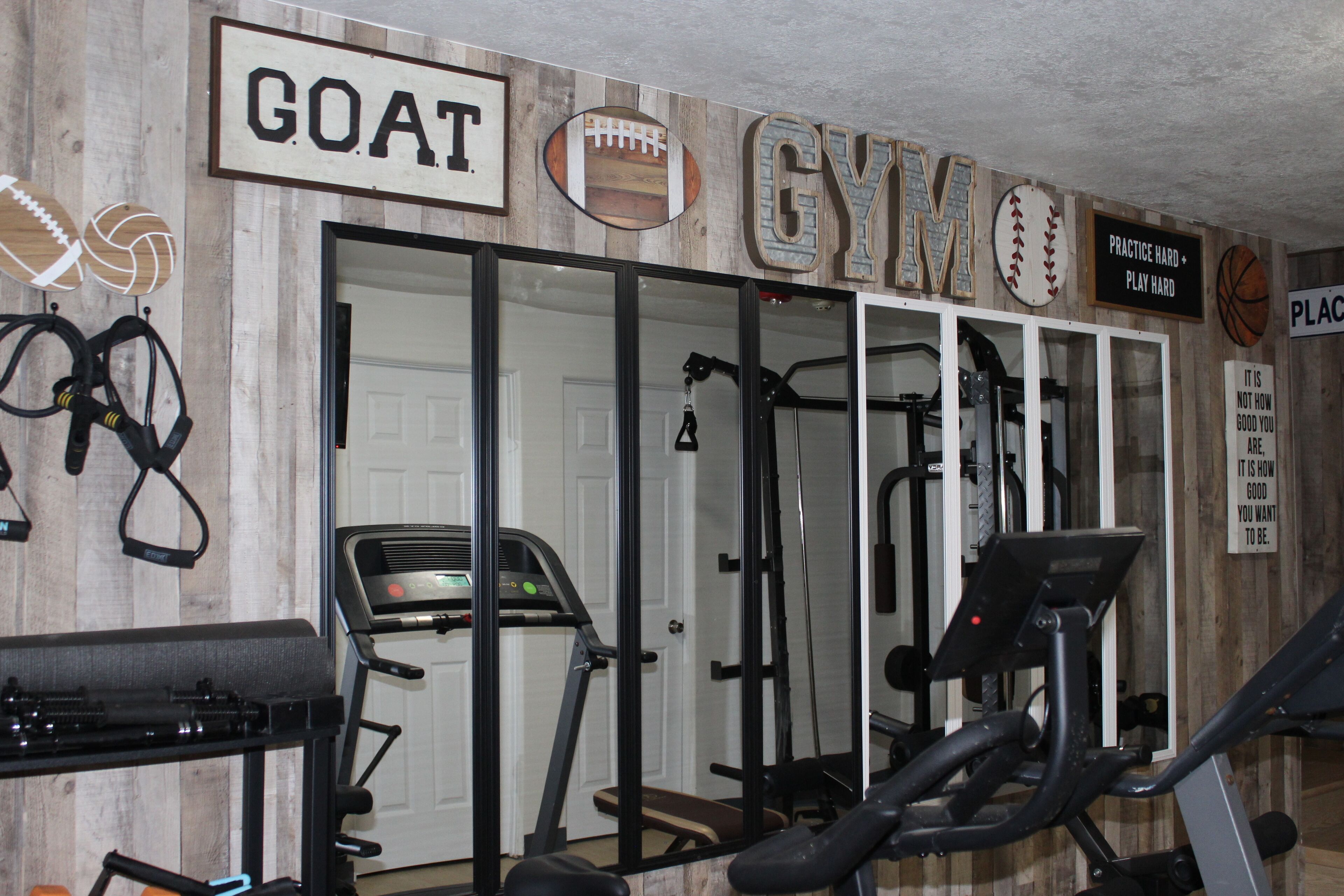 Une salle de sport équipée de matériel d’exercice, d’un tapis de course et ornée d’affiches motivantes.