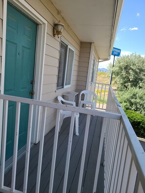 A hotel porch with a teal door, a sign reading "EFFERSON INN", and two white plastic chairs.