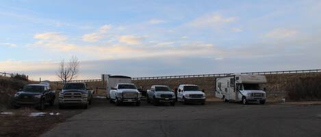 A parking lot with several vehicles, including trucks and a camper, parked in a row.