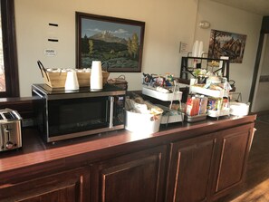 A breakfast bar with a microwave, toaster, and coffee station.
