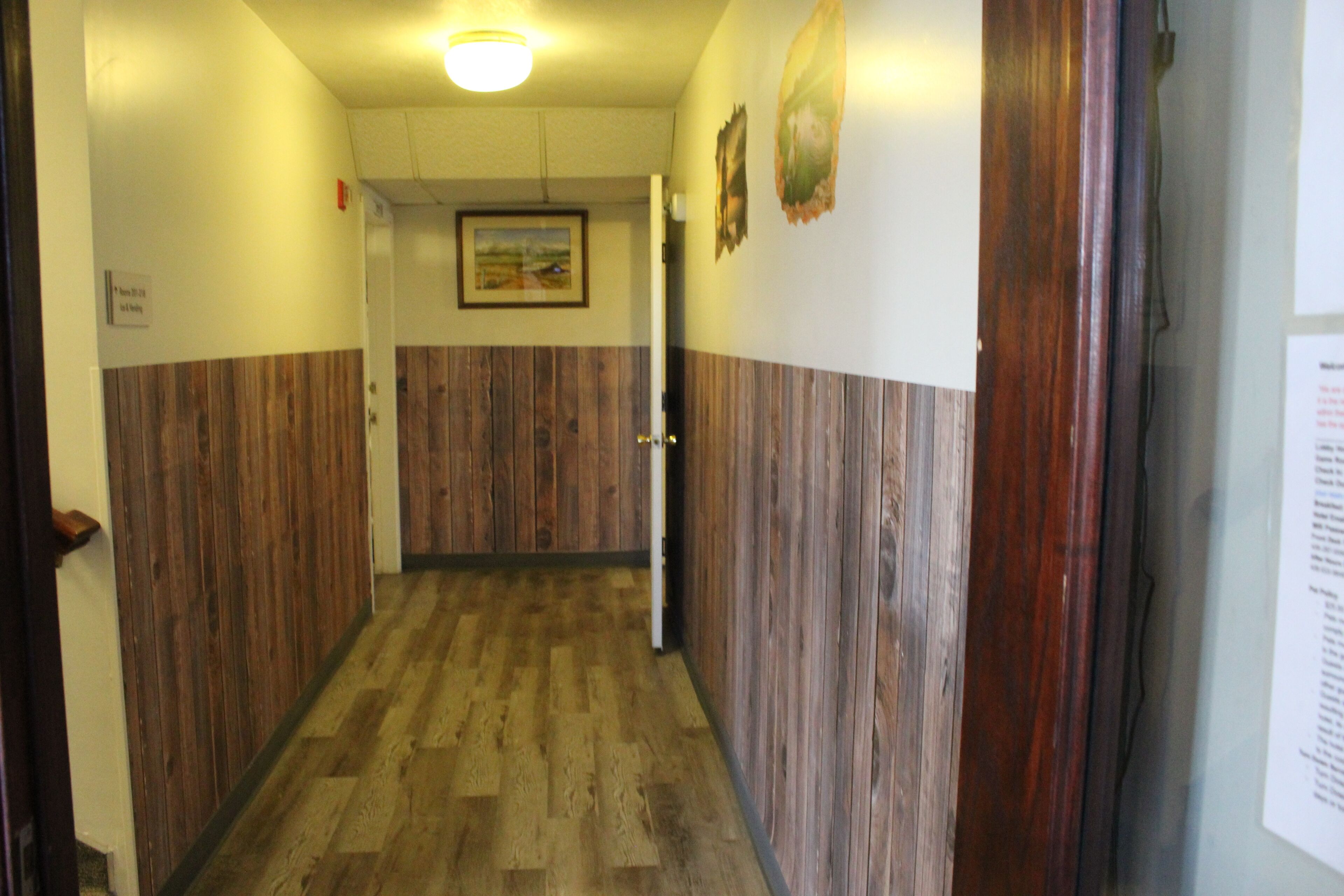 Un couloir aux murs recouverts de lambris en bois et doté d’un plancher en bois.