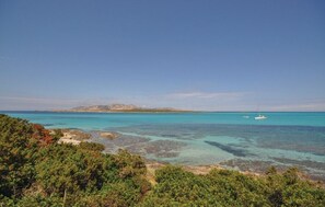 A coastal landscape with clear turquoise waters, rocky shorelines, and dense green vegetation.