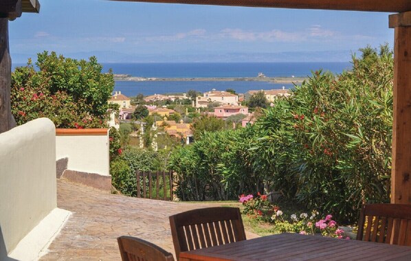 A patio with a table and chairs overlooking a coastal town.