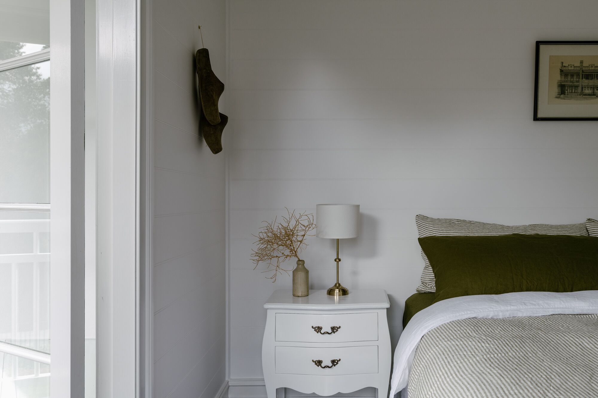 A bedroom with a bed, a nightstand, a lamp, and a framed picture on the wall.