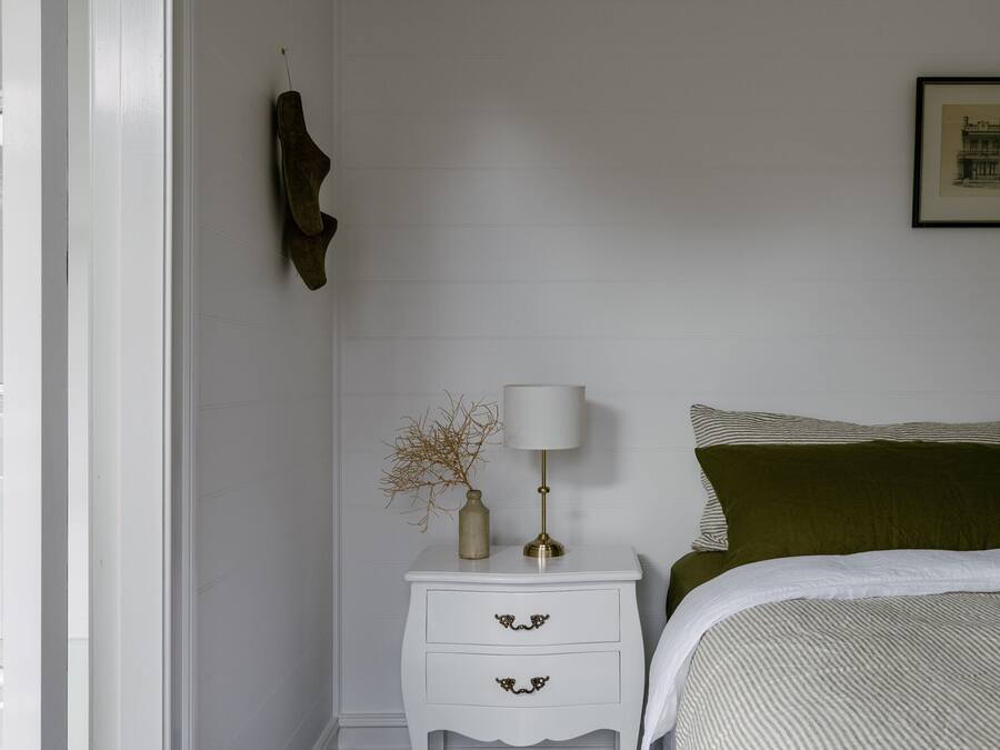 A bedroom with a bed, a nightstand, a lamp, and a framed picture on the wall.